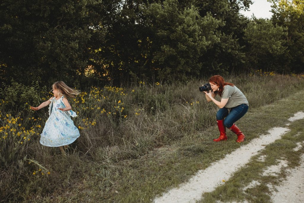 photographer wearing red boots taking portrait of girl twirling