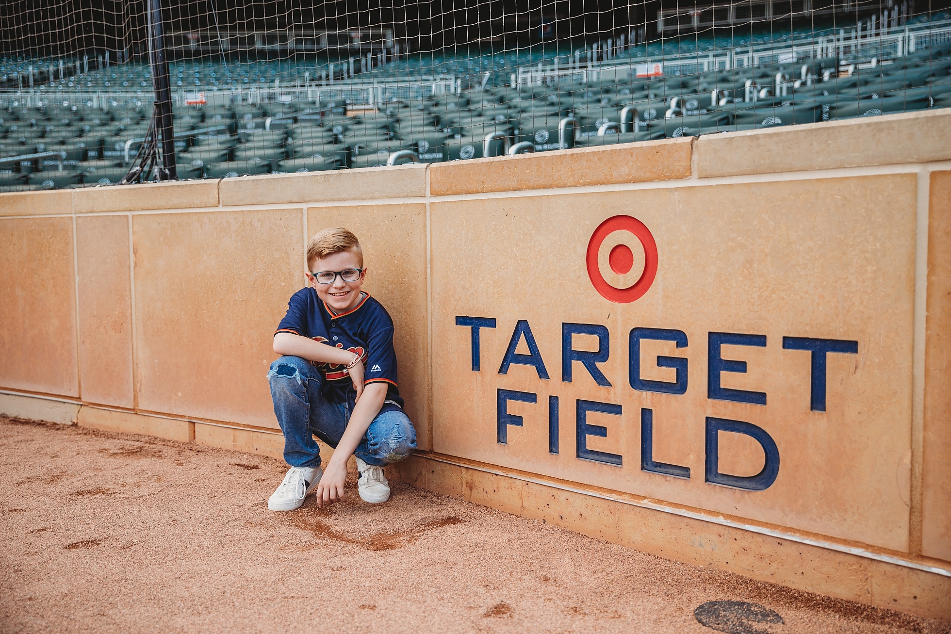 boy sitting in front of target field sign