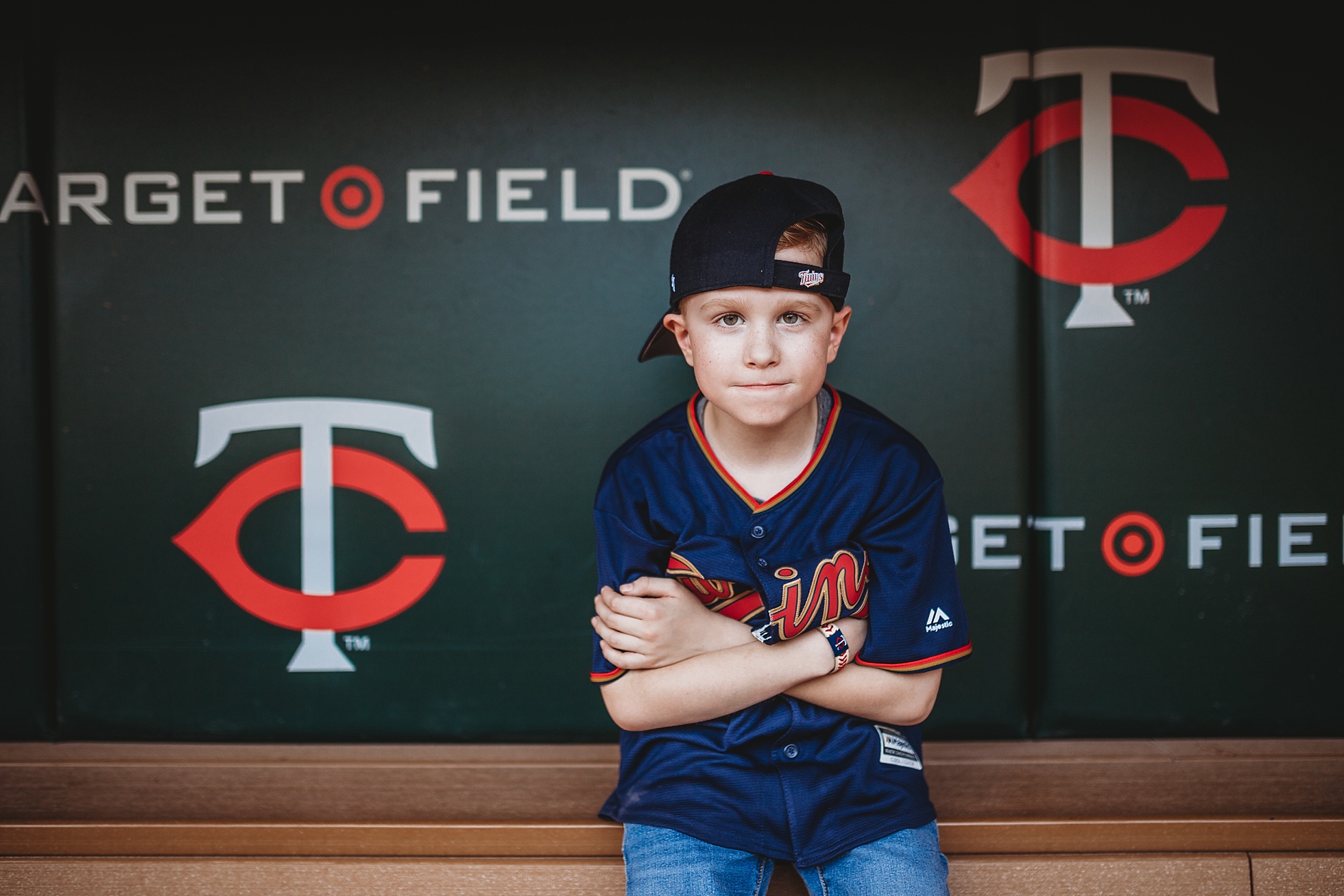 boy sitting in target field dugout with hat on backwards